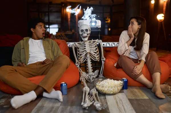 Jeune couple effrayé, squelette et home cinéma — Photo