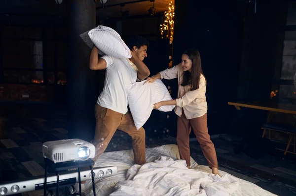 Happy overjoyed family couple fighting with pillow