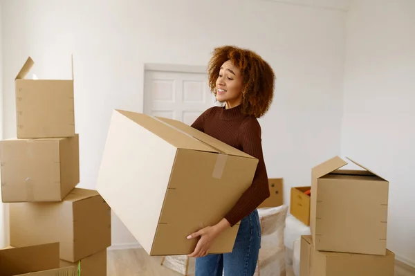 Tired young woman standing among cardboard boxes — Stock Photo, Image