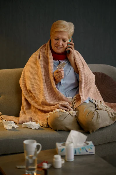 Sick retired woman talking smartphone at home — ストック写真