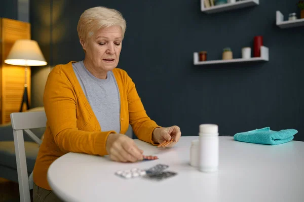 Mujer madura de pelo gris sosteniendo suplementos de píldoras médicas —  Fotos de Stock