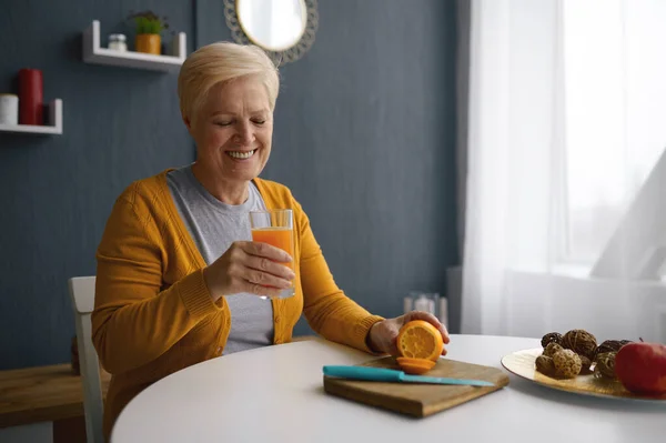 Sorrindo mulher de cabelos grisalhos segurando vidro com suco — Fotografia de Stock