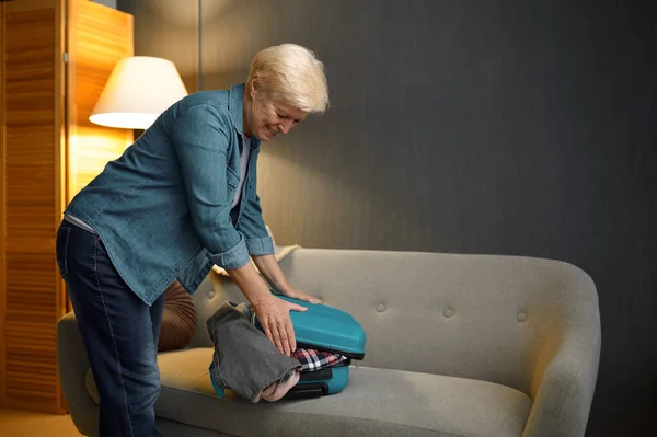 Yaşlı kadın yeni bir yolculuk için bavul hazırlıyor. — Stok fotoğraf