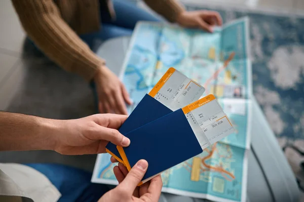 Closeup ticket in hand over guide map — Stock Photo, Image