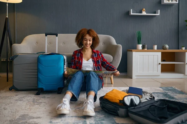 Woman reading travel map surrounded with luggage — Stock Photo, Image