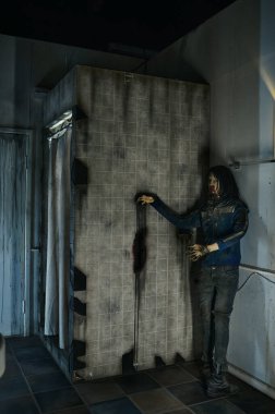Duş kabininin arkasında kan lekeli ürkütücü zombi duruyor.