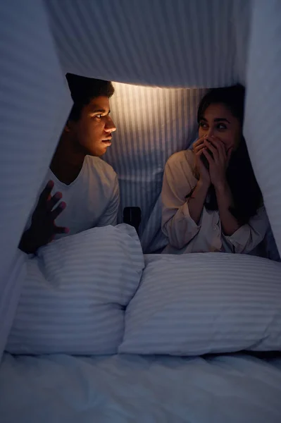 Husband telling wife scary story for under blanket — Stock Photo, Image