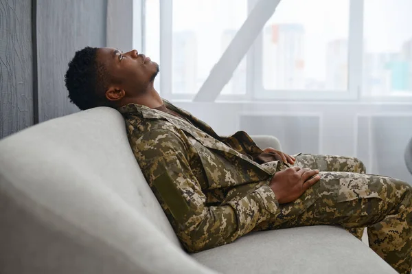 소파에 앉아 군복을 입고 쓰러져 있는 군인 — 스톡 사진