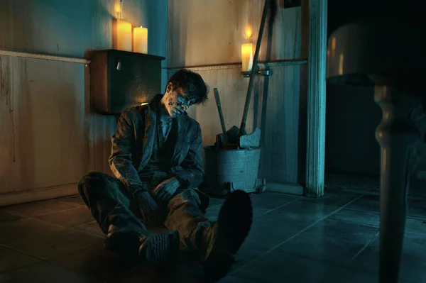 Undead zombie mies istuu wc lattialla — kuvapankkivalokuva