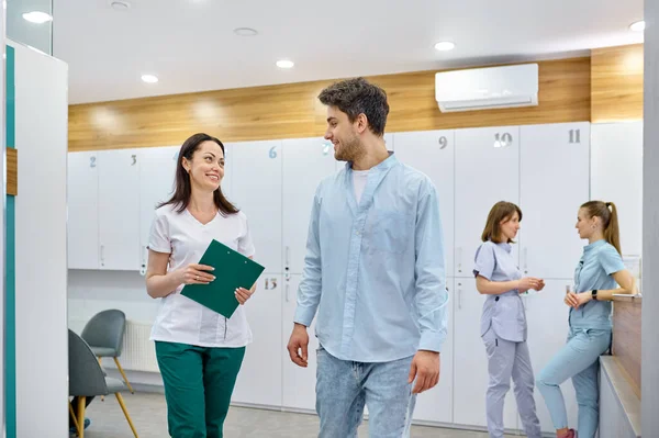 Médico y paciente hablando y caminando pasillo — Foto de Stock