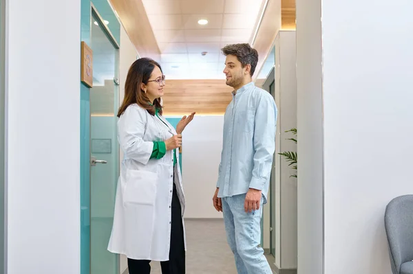 Doctora discutiendo algo con paciente masculino — Foto de Stock