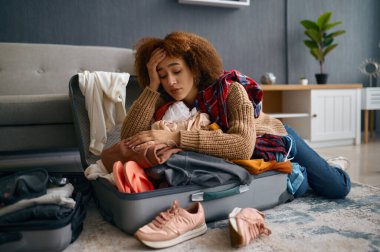 Üzgün genç kadın ve boşaltılmış tatil valizleri.