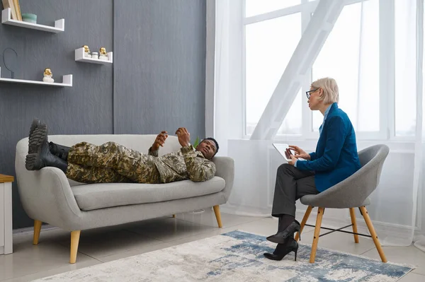 Психолог делает заметки, пока солдат говорит — стоковое фото