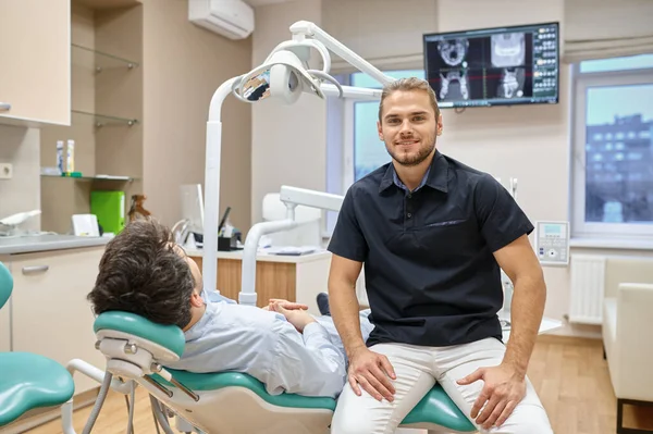 椅子の肖像画の患者の近くに座って歯科医 — ストック写真