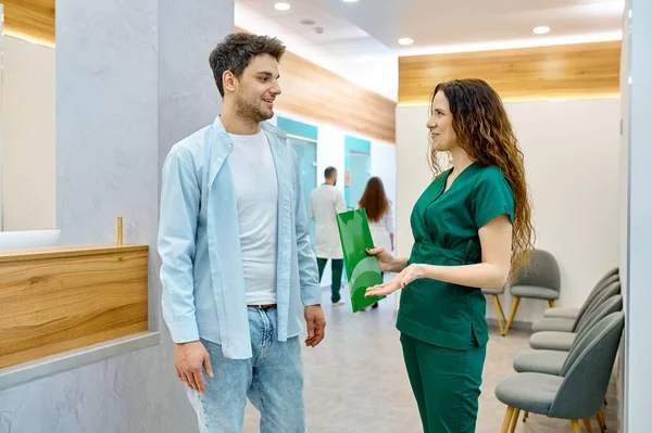 Mand taler med læge i klinik hall - Stock-foto
