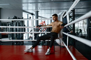 Genç profesyonel boksör boksör boks antrenmanları ve antrenmanlar arasında boks ringinin köşesinde dinleniyor.