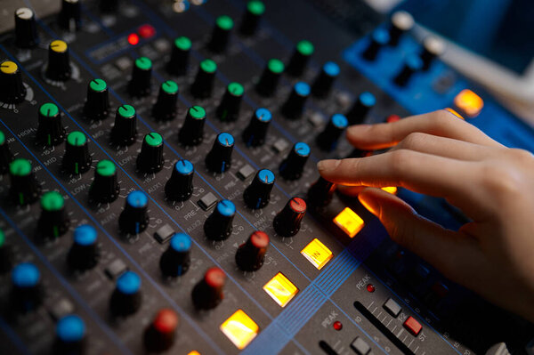 Side view closeup audio engineer hand on sound mixer control panel inside production house