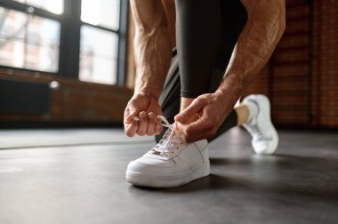 Spor ayakkabılarını bağlayan sporcunun spor salonunda antrenman yapmaya hazırlanması. Fitness ve vücut geliştirme konsepti