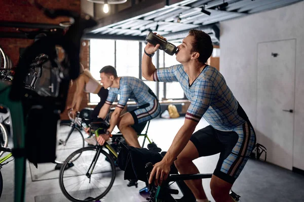 Sportler Trinkt Wasser Während Des Trainings Auf Dem Heimfahrrad Beim — Stockfoto