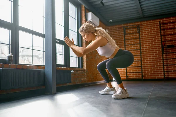 Woman training legs muscles with jump and squat exercise. Wellness and power practice concept