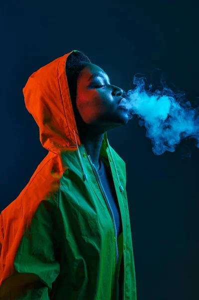 Hipster Γυναίκα Αδιάβροχο Φυσάει Καπνό Από Στόμα Πάνω Από Σκοτεινό — Φωτογραφία Αρχείου