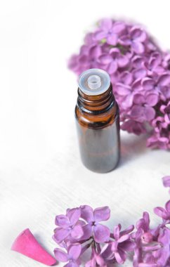 Beyaz arka planda mor leylak çiçekli esaslı yağ ve tütsü şişesi  