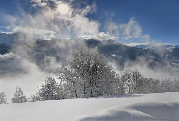 Weiße Schneebedeckte Berglandschaft Vor Wolkenverhangenem Von Der Sonne Erleuchtetem Himmel — Stockfoto
