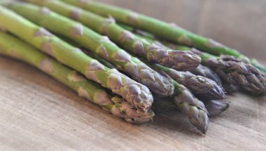 Yeşil, çiğ kuşkonmazın üstüne ahşap bir masa koyun. 