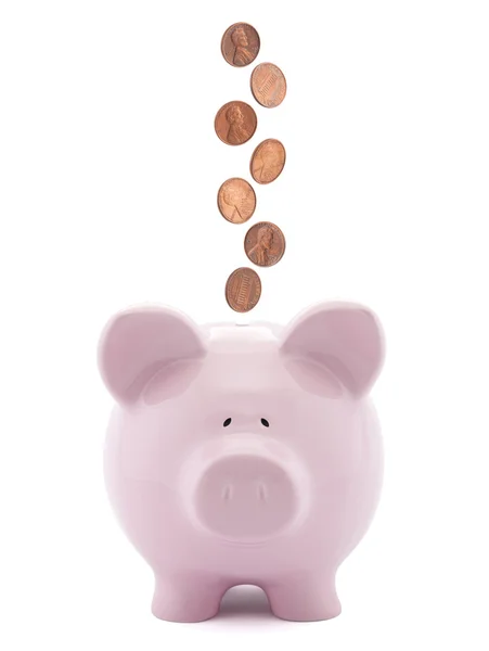 Piggy bank with coins falling into slot — Stock Photo, Image