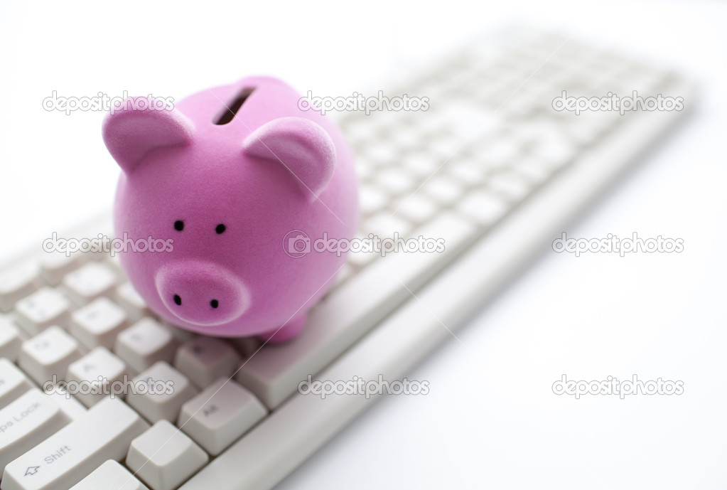 Pink piggy bank on computer keyboard