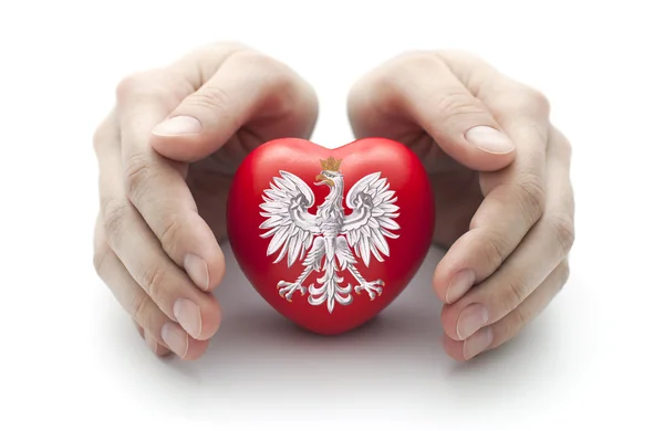 Hands covering Polish coat of arms on a red heart — Stock Photo, Image