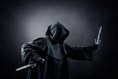 Karanlıkta iki hançerli kapüşonlu suikastçı