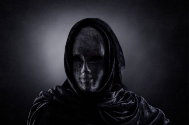 Karanlıkta kapüşonlu pelerinli korkunç bir figür.