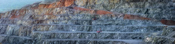 二つの赤い掘削機と糖尿病採石場の階段の壁 石の異なる層を示す広いパノラマ — ストック写真