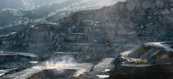 Каменные буровые и дробильные машины, работающие в карьере. Драматический свет, солнечная вспышка