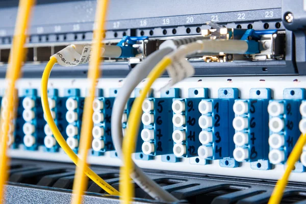 fiber optic cables plugged in network switch panel inside data center