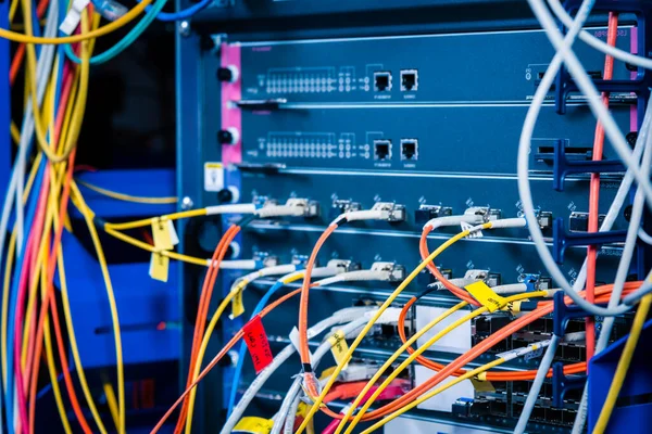 detail of server rack with fiber optic cables attached to front panel switch ports