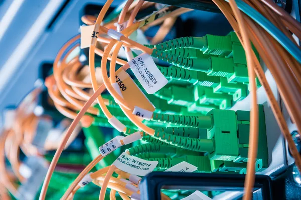 detail of server rack with fiber optic cables attached to front panel switch ports