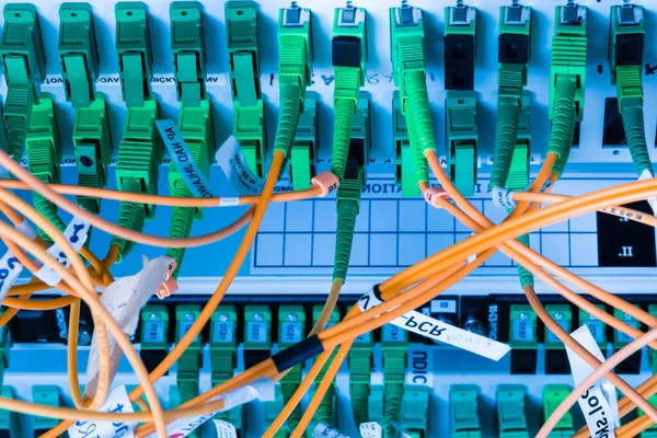 fiber optic cables plugged in network switch panel inside data center