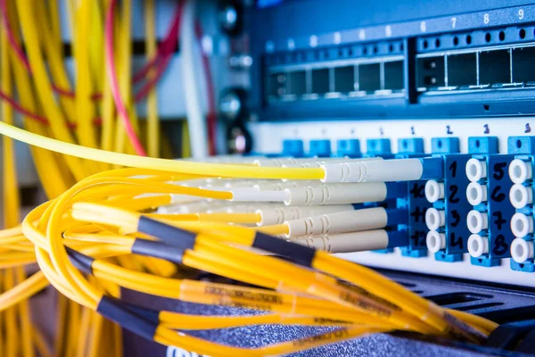 fiber optic cables plugged in network switch panel inside data center