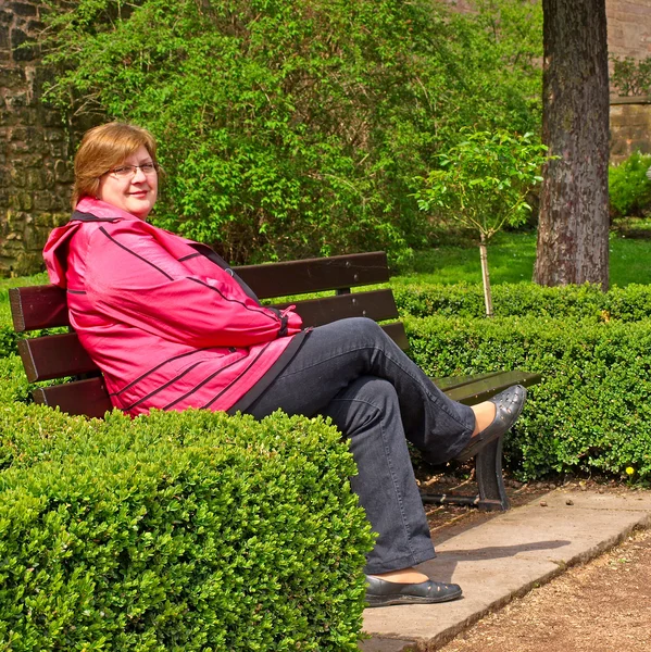 Medelålders kvinna avkopplande på en parkbänk — Stockfoto