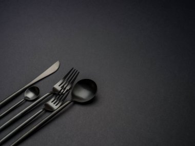 Siyah arkaplan üzerinde siyah çatal bıçak takımı