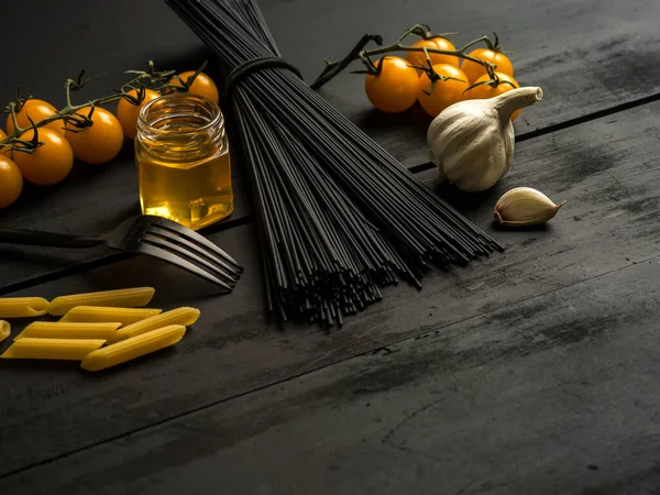Siyah ahşap zemin üzerine makarna malzemesi.