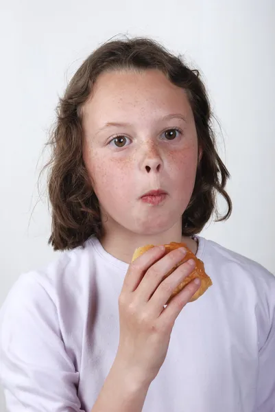 Młoda dziewczyna jedząca bułkę — Zdjęcie stockowe