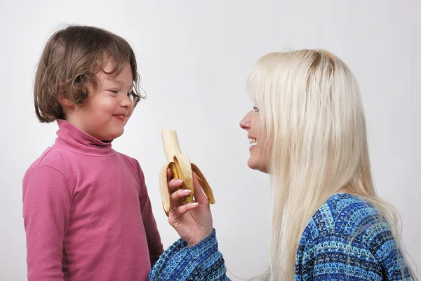 Mom giving a banana to his daughter — Stock Photo, Image