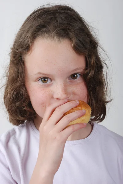 A young girl eating a bun — Stock Photo, Image