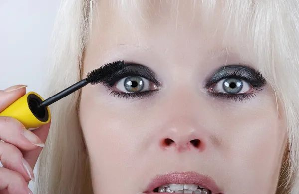 Mulher aplicando maquiagem em seu rosto — Fotografia de Stock