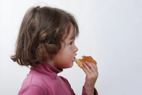 A young girl eating a bun — Stock Photo, Image