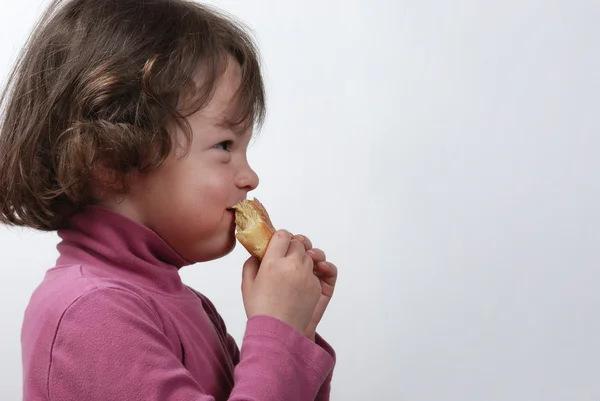 Een jong meisje eet een broodje — Stockfoto