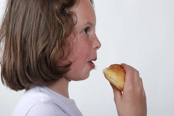 A young girl eating a bun — Stock Photo, Image